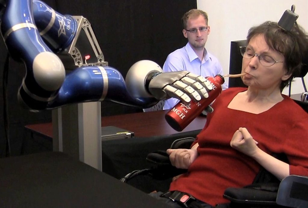 Woman with tetraplegia uses a robotic arm to drink coffee from a bottle.