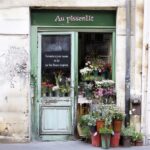 La fleuriste " Au pissenlit " ferme ses portes. On voit sur la porte écrit en français : " Fermeture pour cause de loi sur les fleurs coupées."